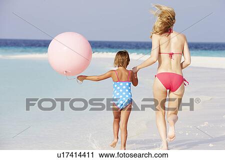 Stock Image - Mother And Daughter Running On Beautiful Beach With Balloon. Fotosearch