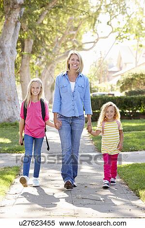 Stock Photography - Mother And Daughters Walking To School On Suburban Street. Fotosearch