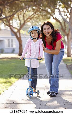 Picture - Mother Teaching Daughter To Ride Scooter. Fotosearch