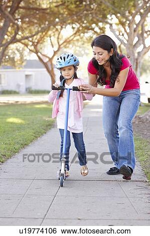 Mother Teaching Daughter To Ride Scooter View Large Photo Image Stock Photograph - Mother Teaching Daughter To Ride Scooter. Fotosearch
