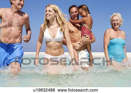 Stock Photo - Multi Generation Family Having Fun In Sea On Beach Holiday. Fotosearch