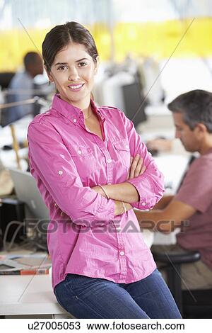 Stock Image - Portrait Of Woman Standing In Busy Creative Office. Fotosearch