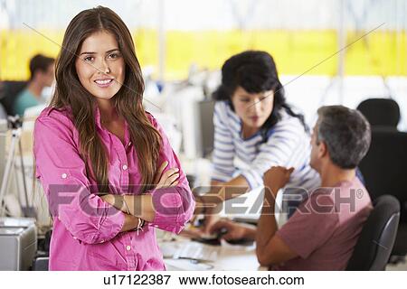 Stock Photo - Portrait Of Woman Standing In Busy Creative Office. Fotosearch