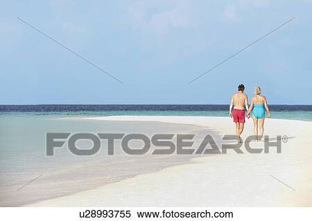Stock Photography - Rear View Of Senior Romantic Couple Walking In Tropical Sea. Fotosearch