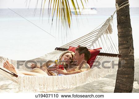 Stock Image - Romantic Couple Relaxing In Beach Hammock. Fotosearch