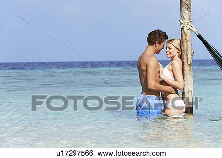 Stock Photograph - Romantic Couple Standing In Beautiful Tropical Sea. Fotosearch