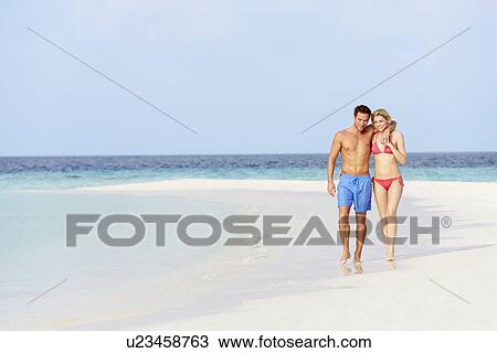 Stock Image - Romantic Couple Walking On Beautiful Tropical Beach. Fotosearch