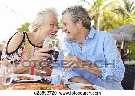 Stock Image - Senior Couple Enjoying Meal In Outdoor Restaurant. Fotosearch