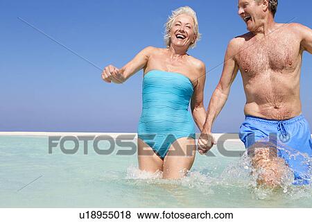 Stock Photo - Senior Couple Having Fun In Sea On Beach Holiday. Fotosearch