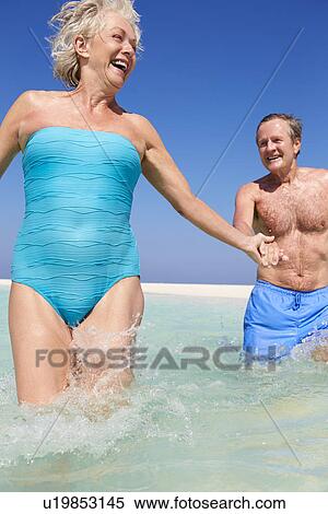 Stock Photography - Senior Couple Having Fun In Sea On Beach Holiday. Fotosearch