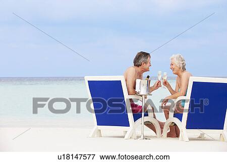 Senior Couple On Beach Relaxing In Chairs Drinking Chapagne View Large Photo Image Stock Photo - Senior Couple On Beach Relaxing In Chairs Drinking Chapagne. Fotosearch