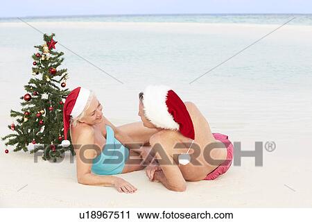 Senior Couple Sitting On Beach With Christmas Tree And Hats View Large Photo Image Stock Image - Senior Couple Sitting On Beach With Christmas Tree And Hats. Fotosearch