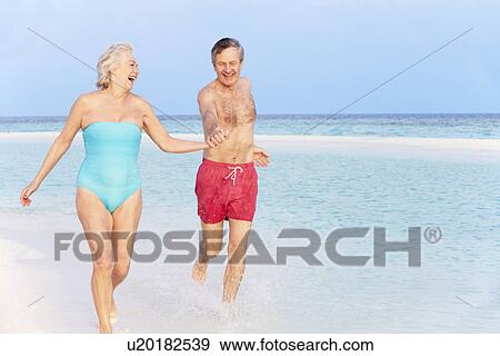 Stock Photo - Senior Couple Splashing In Beautiful Tropical Sea. Fotosearch
