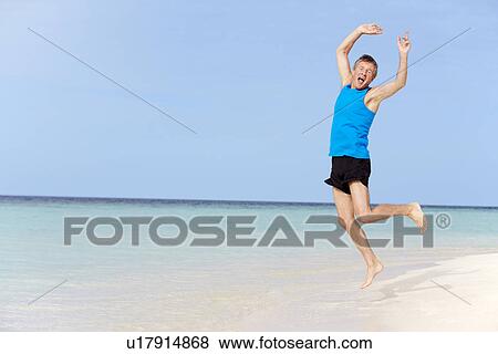 Stock Photo - Senior Man Jumping On Beautiful Beach. Fotosearch