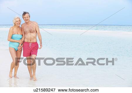 Stock Photo - Senior Romantic Couple Walking In Beautiful Tropical Sea. Fotosearch