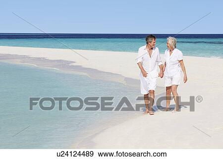 Stock Photo - Senior Romantic Couple Walking On Beautiful Tropical Beach. Fotosearch