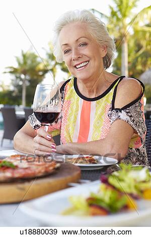 Stock Photo - Senior Woman Enjoying Meal In Outdoor Restaurant. Fotosearch