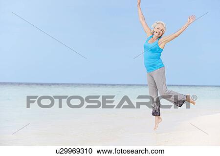 Stock Image - Senior Woman Jumping On Beautiful Beach. Fotosearch