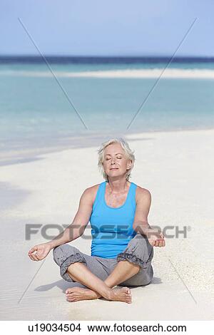 Picture - Senior Woman Meditating On Beautiful Beach. Fotosearch