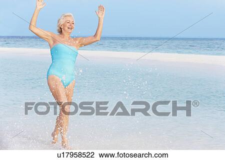 Stock Image - Senior Woman Splashing In Beautiful Tropical Sea. Fotosearch