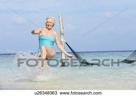 Stock Image - Senior Woman Splashing In Beautiful Tropical Sea. Fotosearch