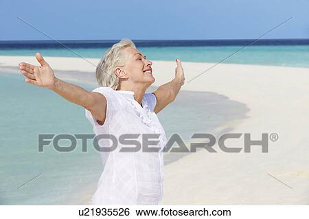 Stock Photograph - Senior Woman With Arms Outstretched On Beautiful Beach. Fotosearch
