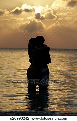 Stock Image - Silhouette Of Romantic Couple Standing In Sea. Fotosearch