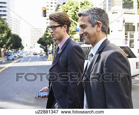 Stock Photo - Two Businessman Chatting Whilst Crossing Street. Fotosearch