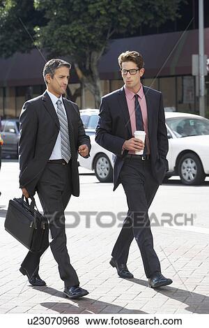 Stock Photo - Two Businessman Chatting Whilst Crossing Street. Fotosearch