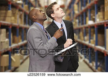 Stock Photo - Two Businessmen Having Discussion In Warehouse. Fotosearch