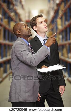 Stock Photography - Two Businessmen Having Discussion In Warehouse. Fotosearch