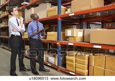 Stock Image - Two Businessmen With Clipboard In Warehouse. Fotosearch