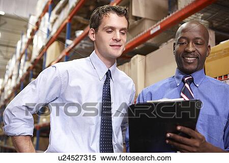 Stock Photography - Two Businessmen With Clipboard In Warehouse. Fotosearch