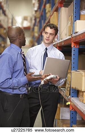 Stock Photography - Two Businessmen With Laptop In Warehouse. Fotosearch