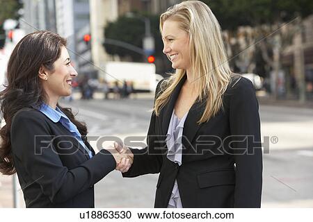 Stock Image - Two Businesswomen Shaking Hands Outside Office. Fotosearch