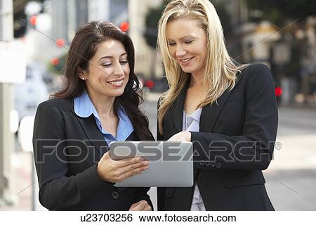 Stock Photograph - Two Businesswomen Using Digital Tablet Outside Office. Fotosearch