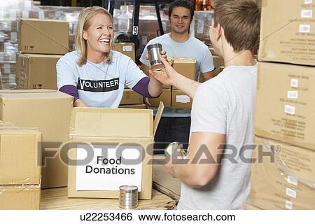 Stock Photograph - Volunteers Collecting Food Donations In Warehouse. Fotosearch