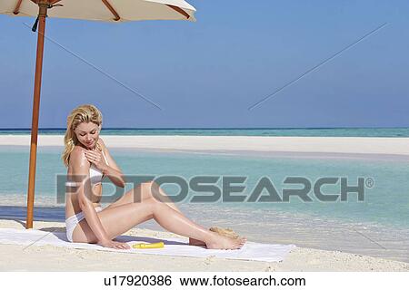 Stock Photograph - Woman Applying Sun Lotion On Beach Holiday. Fotosearch