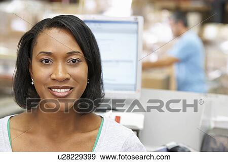 Stock Photo - Woman At Computer Terminal In Distribution Warehouse. Fotosearch