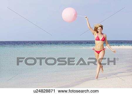 Stock Image - Woman In Bikini Running On Beautiful Beach With Balloon. Fotosearch
