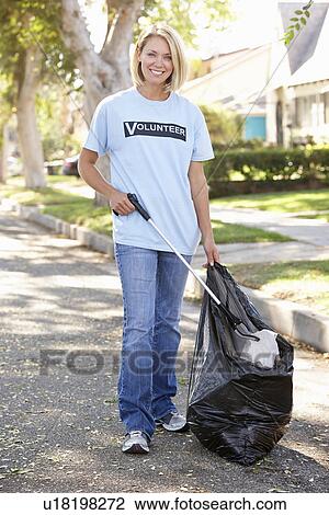 Stock Image - Woman Picking Up Litter In Suburban Street. Fotosearch