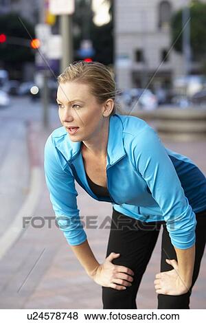 Stock Photo - Woman Resting Whilst Running Along Urban Street. Fotosearch
