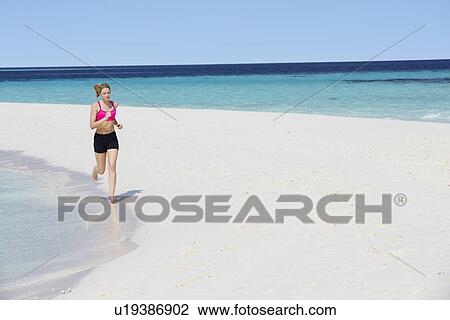 Stock Image - Woman Running On Beautiful Beach. Fotosearch