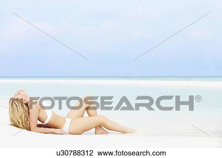 Stock Image - Woman Sunbathing On Beautiful Beach Holiday. Fotosearch