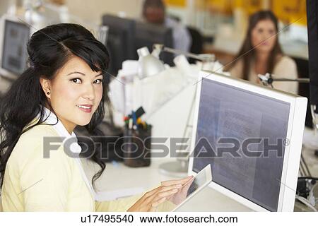 Stock Image - Woman Using Digital Tablet In Busy Creative Office. Fotosearch