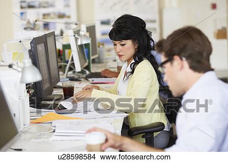 Picture - Woman Working At Desk In Busy Creative Office. Fotosearch