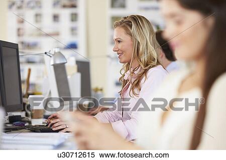 Woman Working At Desk In Busy Creative Office View Large Photo Image Stock Photography - Woman Working At Desk In Busy Creative Office. Fotosearch