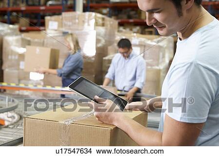 Worker Using Tablet Computer In Distribution Warehouse View Large Photo Image Picture - Worker Using Tablet Computer In Distribution Warehouse. Fotosearch
