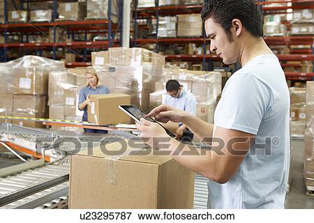 Worker Using Tablet Computer In Distribution Warehouse View Large Photo Image Stock Photo - Worker Using Tablet Computer In Distribution Warehouse. Fotosearch