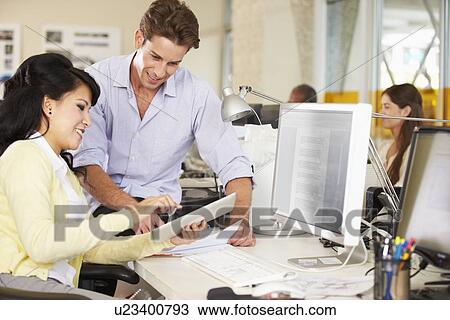 Stock Image - Workers Using Digital Tablet In Busy Creative Office. Fotosearch